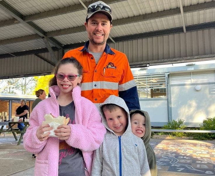 Student and her two younger brothers and their Father, enjoying a bacon and egg roll at the father's day breakfast